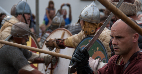 A Viking re-enactor, with a helmet and a sword, stands ready during a historical battle at Norsk Høstfest.