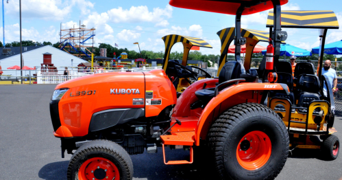 Bright orange tractor at Diggerland in NJ under a blue sky with white clouds