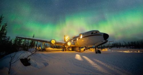 The northern lights shine bright behind a private jet Airbnb in Alaska.