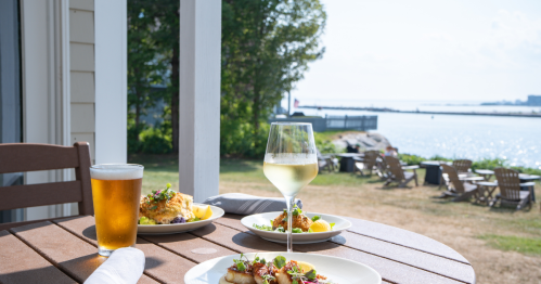 An outside table filled with food, beer, and wine overlooking the water at the Port Fish & Chop House in Kennebunkport, Maine.
