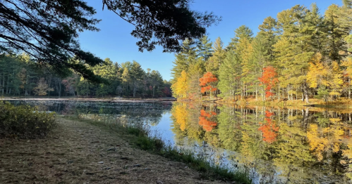 peck pond at Rhode Island's Pulaski State Park with a beach and fall foliage along its shore
