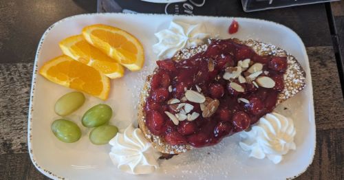 A plate of food that includes oranges, grapes, bread, and cherries.