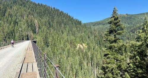 A girl rides her bike along a trestle bridge on the Route of Hiawatha Trail in northern Idaho.