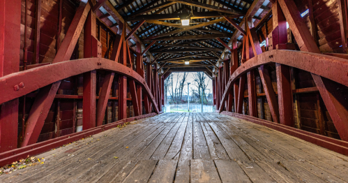 Interior view of Shearer's Covered Bridge in Lancaster County, PA, with a wooden floor and red timber arches.