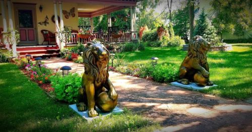 Two gold lawn lions mark the entrance to an old home.