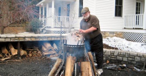A man pouring fish into a pot outside for a fish boil.