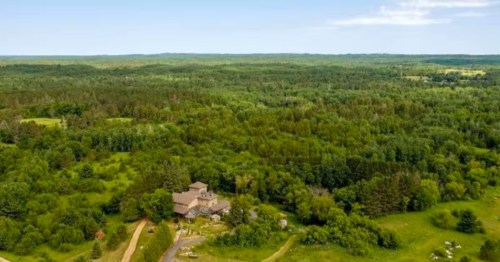 A castle-style, stone home is surrounded by green forests in northern Minnesota.