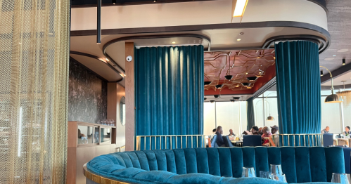 Teal booth seating and archways with diners at tables in the background