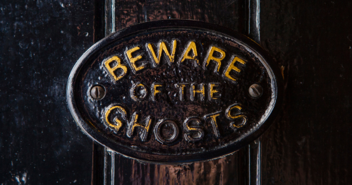 A metal sign on a door informs of ghosts.