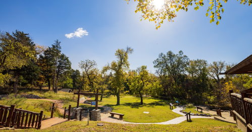 view of a paved path, a footbridge, and a bench at boiling springs state park in oklahoma during fall