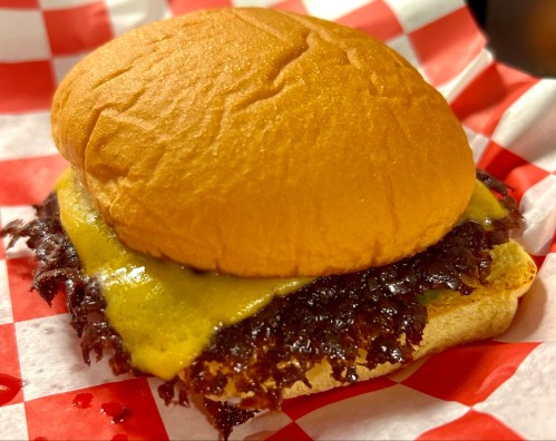 A burger nestled inside a red and white checkered basket, ready to eat