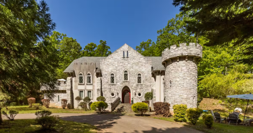 Exterior of stone castle Airbnb with stately trees surrounding.