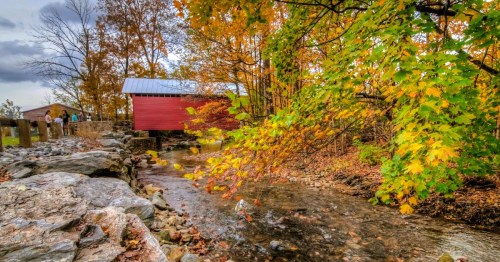 A historic covered bridge surrounded by fall foliage and a flowing creek in Thurmont, a mountain town in Maryland
