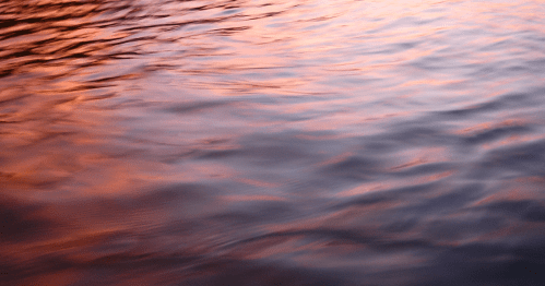 closeup of water ripples with a sunset reflected on the water
