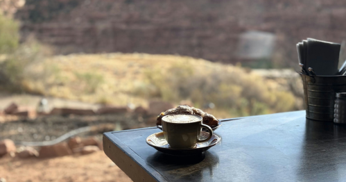 A coffee and a croissant on a table against a large window
