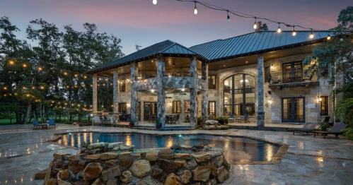Exterior of castle Airbnb in Florida, showing pool and twinkle lights and stone detail under a pink and blue sky in the evening.