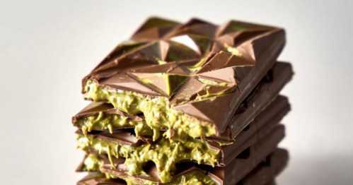 A stack of broken chocolate bars with a green pistachio and shredded phyllo dough filling oozing out.