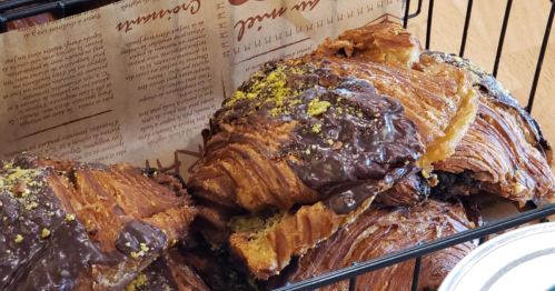 A basket of Dubai chocolate croissants, topped with chocolate and crushed pistachios.
