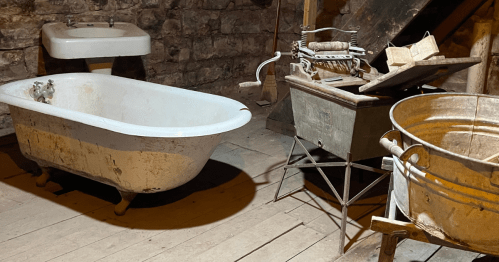 A white tub, sink, and grooming equipment with wooden boards and dusty brick in the underground tunnels in Ellinwood