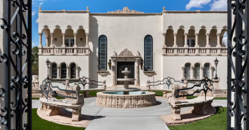 A gate opens to a view of a stately castle-like villa in New Mexico.