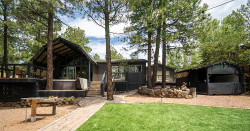 exterior of the tranquil retreat airbnb, a modern cabin with a hot tub, deck, and lawn in munds park arizona