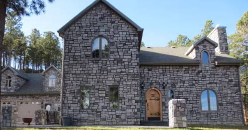 A large stone castle with a prominent wooden arched door and multiple windows.