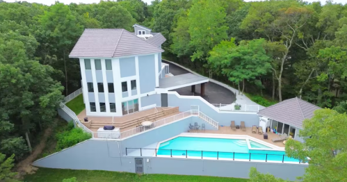 Exterior of grey Airbnb castle-like house with lots of windows and private swimming pool