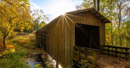 Historic Cromer's Mill Covered Bridge in Roytson GA, surrounded by fall foliage.