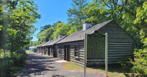 A row of historic log cabins stands beside a walking path at Fort Wilkins State Park.