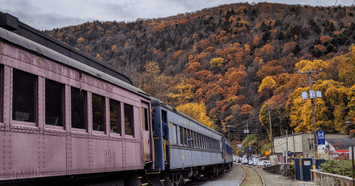 a train rolls through the mountain town of jim thorpe, pa, with late fall foliage colors