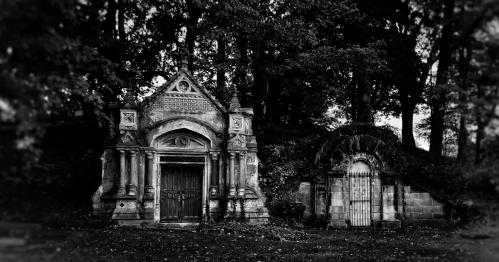 A black and white view of a mausoleum in a cemetery.
