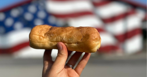 A pepperoni roll held up in front of an American flag