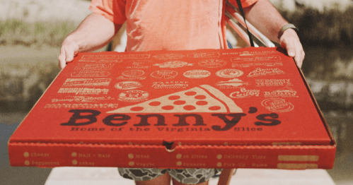 person holds a giant red pizza box with "Benny's" on the front