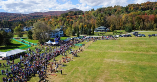 Aerial view of epic pumpkin launch at an open field with crowd and stunning foliage and mountain views in VT.