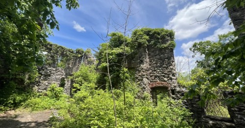 A crumbling stone castle is being reclaimed by vividly green nature.