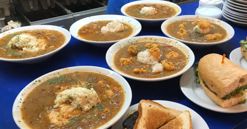 Six bowls of gumbo and some sandwiches sit on a blue counter waiting to be devoured at Chef Ron's Gumbo Stop in Metairie, LA