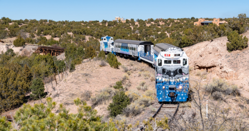 Sky Railway train in Santa Fe, NM comes around a bend in a desert area with scrub brush and sagebrush.