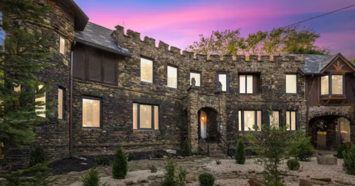 Stunning sunset view of a stone castle with turrets and lush landscaping.
