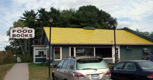 A restaurant with a yellow roof and cars parked outside.