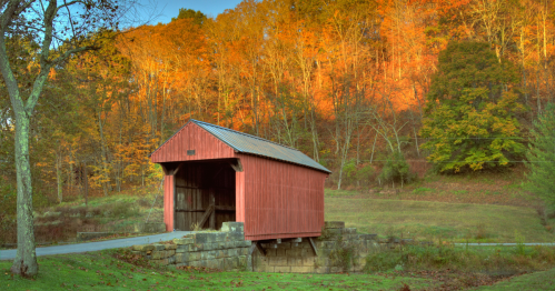 a red covered bridge surrounded by fall foliage in west virginia