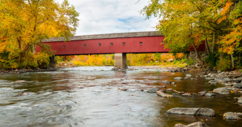 a historic red covered bridge known as the west cornwall covered bridge spans the Housatonic River in CT