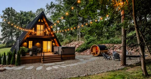 A cabin deck featuring a large hot tub and a separate cedar barrel sauna for guests.