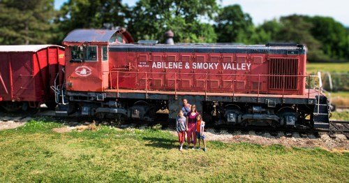 family of four standing in front of a vintage red train