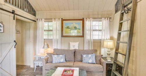 A bright living room inside of a cabin with a loft ladder.
