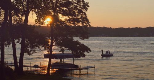 Sunset over a lake with people fishing.