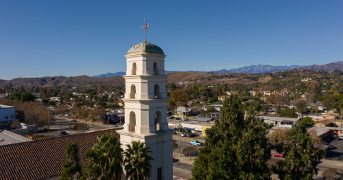 A historic building sits in the foreground of the Pomona, California, skyline.