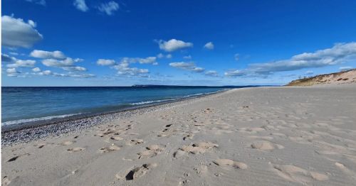 A sandy shoreline and a blue lake.