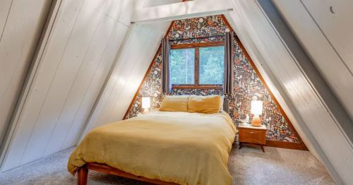 A bed with yellow bedding in an A-frame cabin.