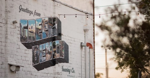Mural on exterior wall that says "Green Bench"