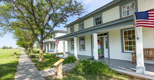 White, plantation style two-story house with pillars and a porch with an American flag